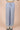 Light blue wide-leg pants with an elastic drawstring waist, front pockets, and a relaxed fit, styled with a cream crop top and platform sneakers against a beige background.