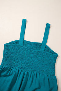 A teal blue sleeveless dress with a smocked bodice and adjustable shoulder straps, displayed against a neutral background.