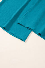 Turquoise blue linen fabric with rolled hems and natural texture, displayed flat against a white background showing the garment's drape and construction details.