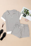 A black and white striped short-sleeve t-shirt and matching striped shorts set laid flat on a beige background, styled with black sandals, a watch, and decorative accessories including photos and a perfume bottle.
