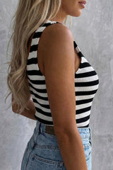 A woman wearing a black and white horizontal striped sleeveless ribbed tank top paired with light blue denim, shown from the side profile.