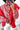 A red and white gingham check blouse with ruffled front placket and voluminous sleeves, paired with a solid red cardigan. The outfit is styled with gold circular earrings and red nail polish.