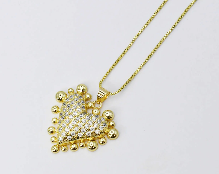 Gold-toned heart pendant necklace featuring cubic zirconia crystals covering the center with decorative gold ball accents around the border, suspended from a matching box chain.