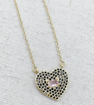 A gold-tone heart-shaped pendant necklace featuring black rhinestone pave detailing with a pale pink gemstone center, suspended from a delicate gold chain.