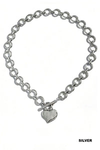 A silver-toned chain necklace with interlocking circular links and a polished heart-shaped pendant hanging from a toggle clasp.
