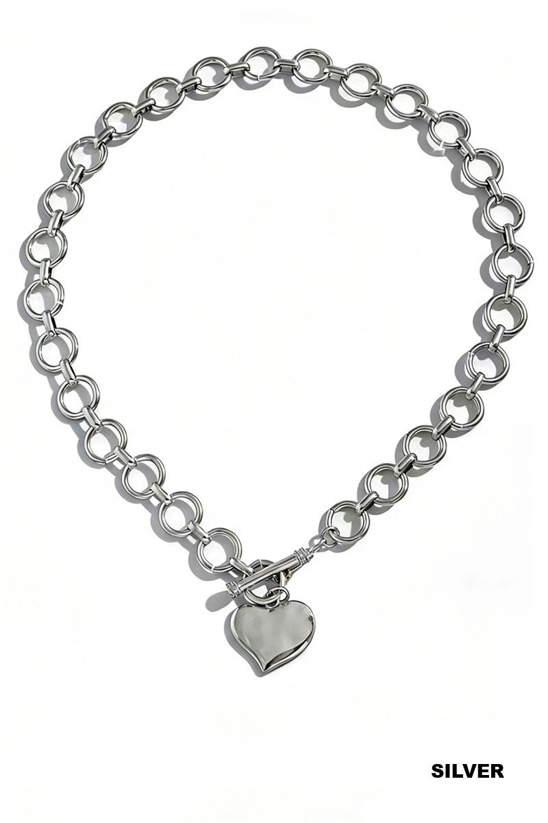 A silver-toned chain necklace with interlocking circular links and a polished heart-shaped pendant hanging from a toggle clasp.