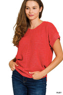 A woman wearing a ruby red short-sleeved knit sweater with a textured waffle knit pattern, paired with dark blue jeans. The sweater features a classic crew neckline and relaxed fit.