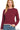 A woman wearing a dark burgundy long-sleeve crop sweater with a crew neckline and contrasting cream-colored trim, paired with blue jeans.