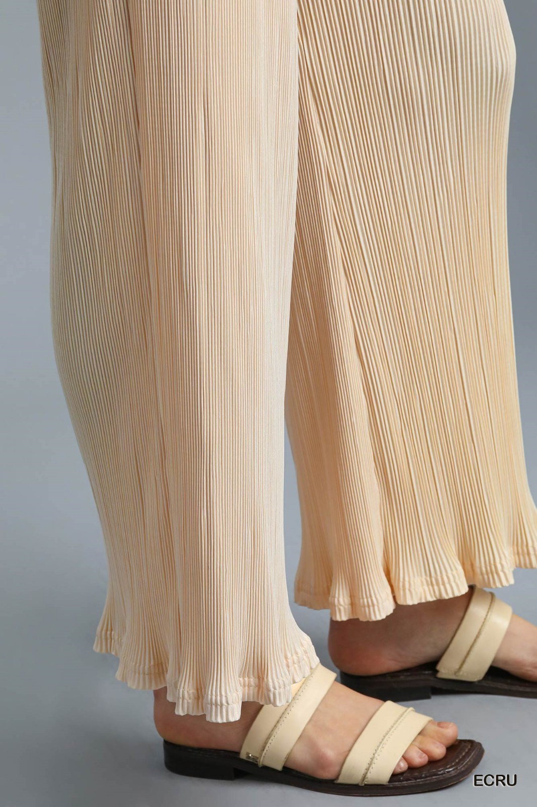Cream-colored ribbed wide-leg pants with a flowing silhouette, paired with beige strappy sandals featuring a dark sole.