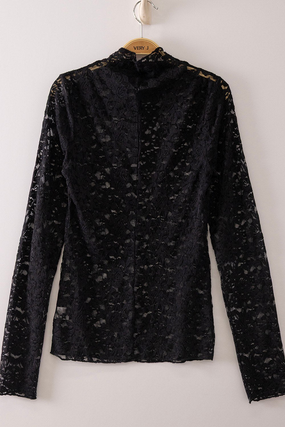 Black lace long-sleeve blouse with an allover floral pattern and high neckline, displayed on a wooden hanger against a neutral background.