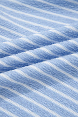 Close-up of a blue and white striped knit fabric showing vertical ribbed texture and diagonal folds in the material.