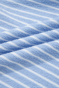 Close-up of a blue and white striped knit fabric showing vertical ribbed texture and diagonal folds in the material.