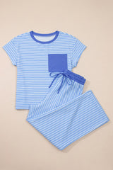 A two-piece children's pajama set in light blue and white stripes featuring a short-sleeved t-shirt with a solid blue chest pocket and matching striped shorts with an elastic drawstring waist.