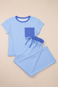 A two-piece children's pajama set in light blue and white stripes featuring a short-sleeved t-shirt with a solid blue chest pocket and matching striped shorts with an elastic drawstring waist.