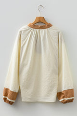 A cream-colored long-sleeve sweatshirt with a textured quilted fabric, featuring a tan ribbed crew neckline and matching tan ribbed cuffs on the sleeves, displayed on a wooden hanger against a white background.