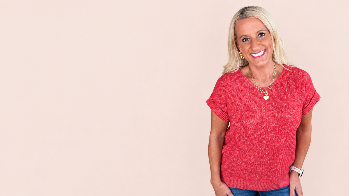 Amy in a coral knit top, welcoming you to the Simply Amy story