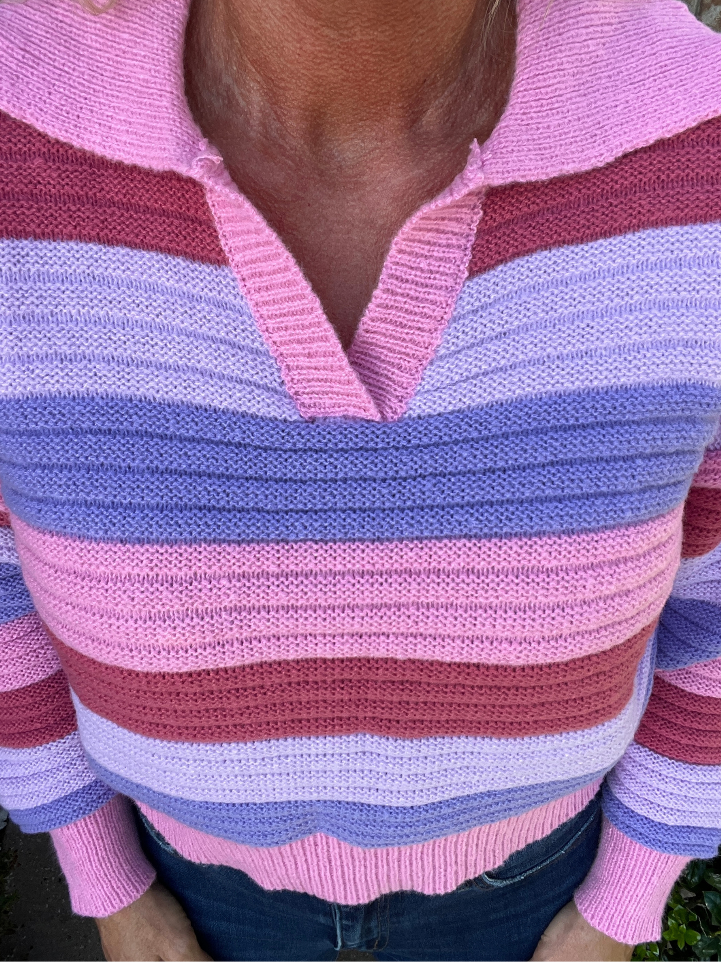 Close-up of a person wearing a pink and purple striped sweater.