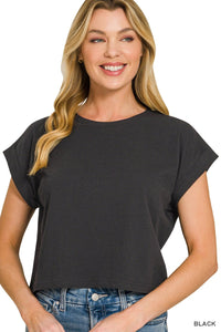 A woman wearing a black short-sleeved crew neck t-shirt with rolled cuffs, paired with blue denim jeans. The shirt has a relaxed, casual fit.