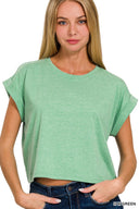 A woman wearing a mint green heathered crop t-shirt with short rolled sleeves and a crew neckline, paired with dark blue jeans.