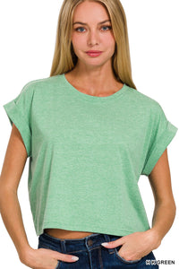A woman wearing a mint green heathered crop t-shirt with short rolled sleeves and a crew neckline, paired with dark blue jeans.